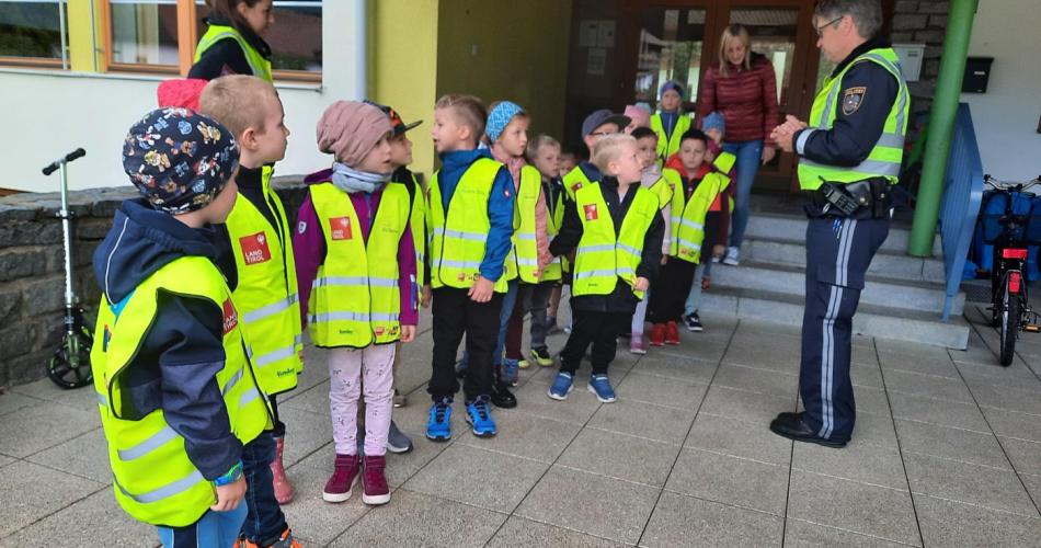 Der Polizist erklärt das richtige Überqueren der Straße.